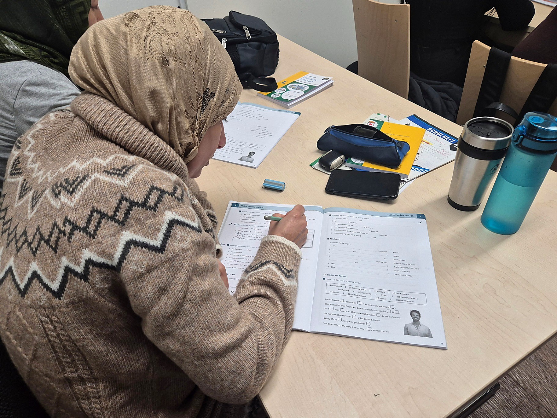Teilnehmerin arbeitet konzentriert mit einem Deutsch-Lehrbuch im Kurs von YAPA Germany e.V.