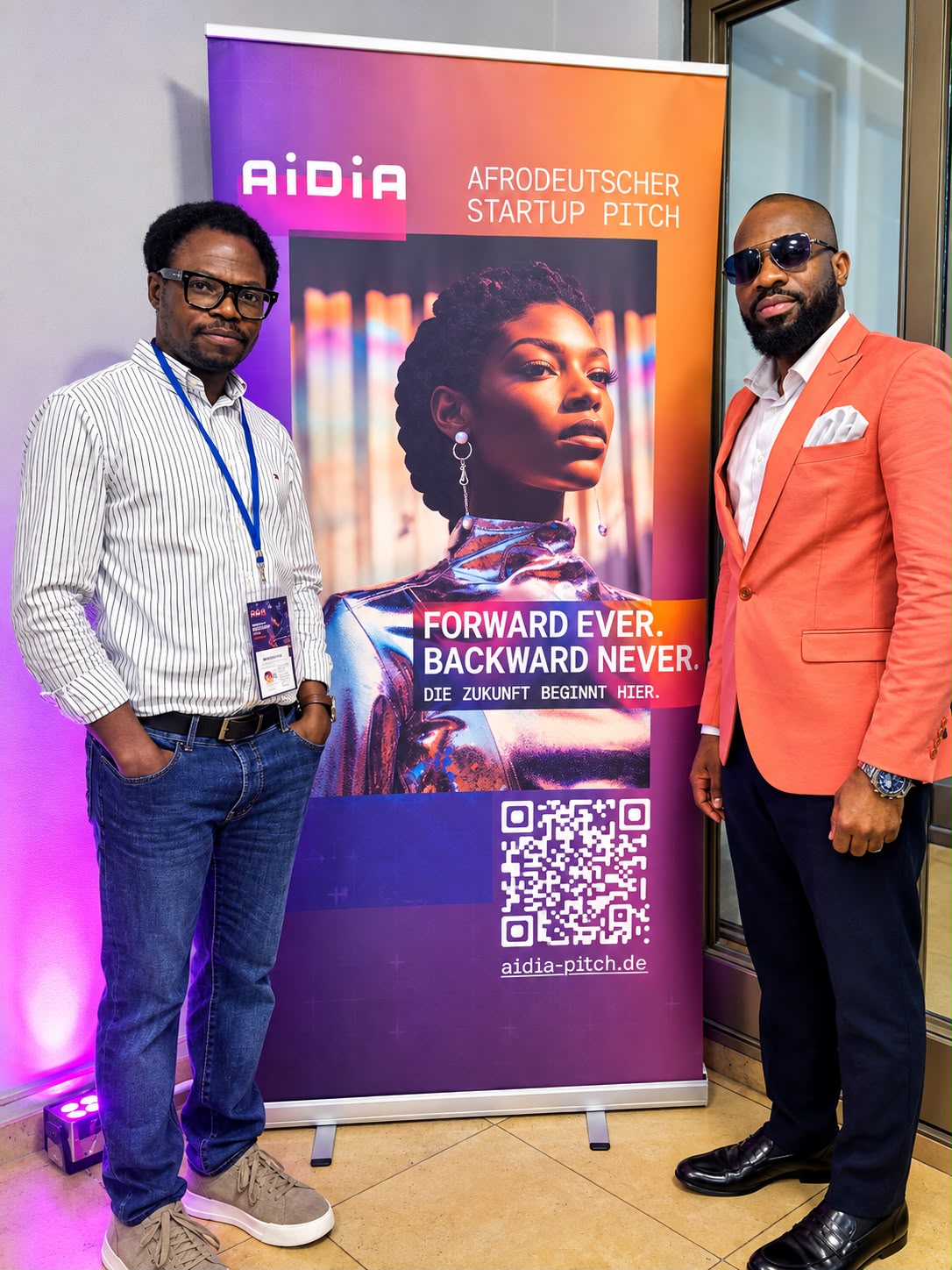 Zwei Teilnehmer des Build-Up-Programms vor einem Roll-up-Banner beim Afrodeutschen Startup Pitch AiDiA in Hamburg